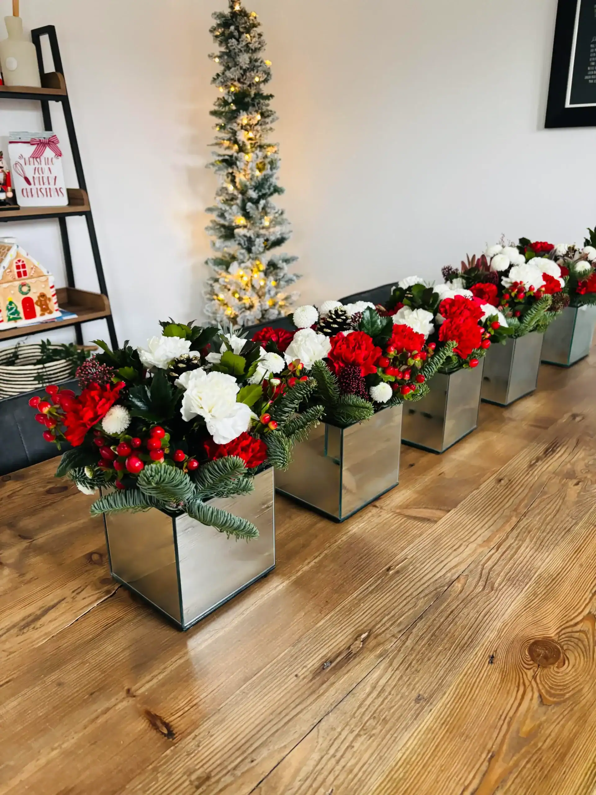 Elegant Christmas floral displays with red, white, and green accents in modern silver pots.