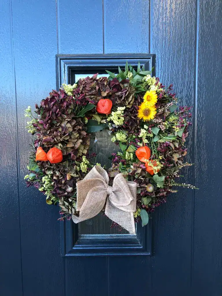 Decorative floral wreath featuring vibrant flowers and a beige bow, perfect for spring or special oc.
