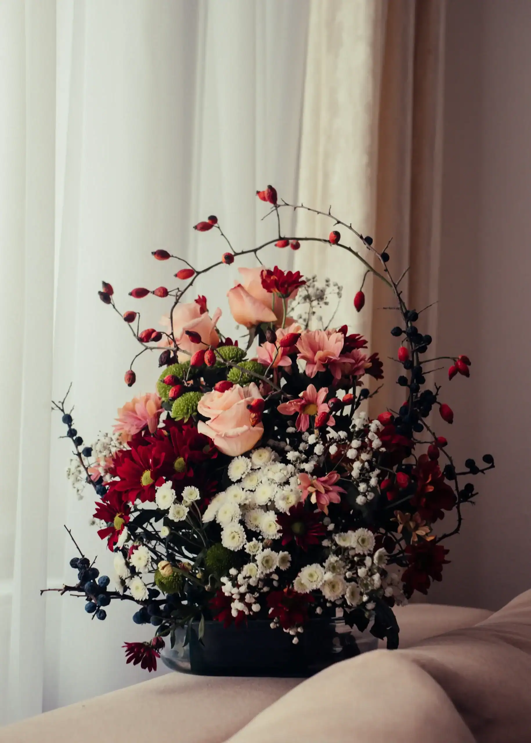 Elegant floral arrangement with pink, red, and white flowers in a black vase.