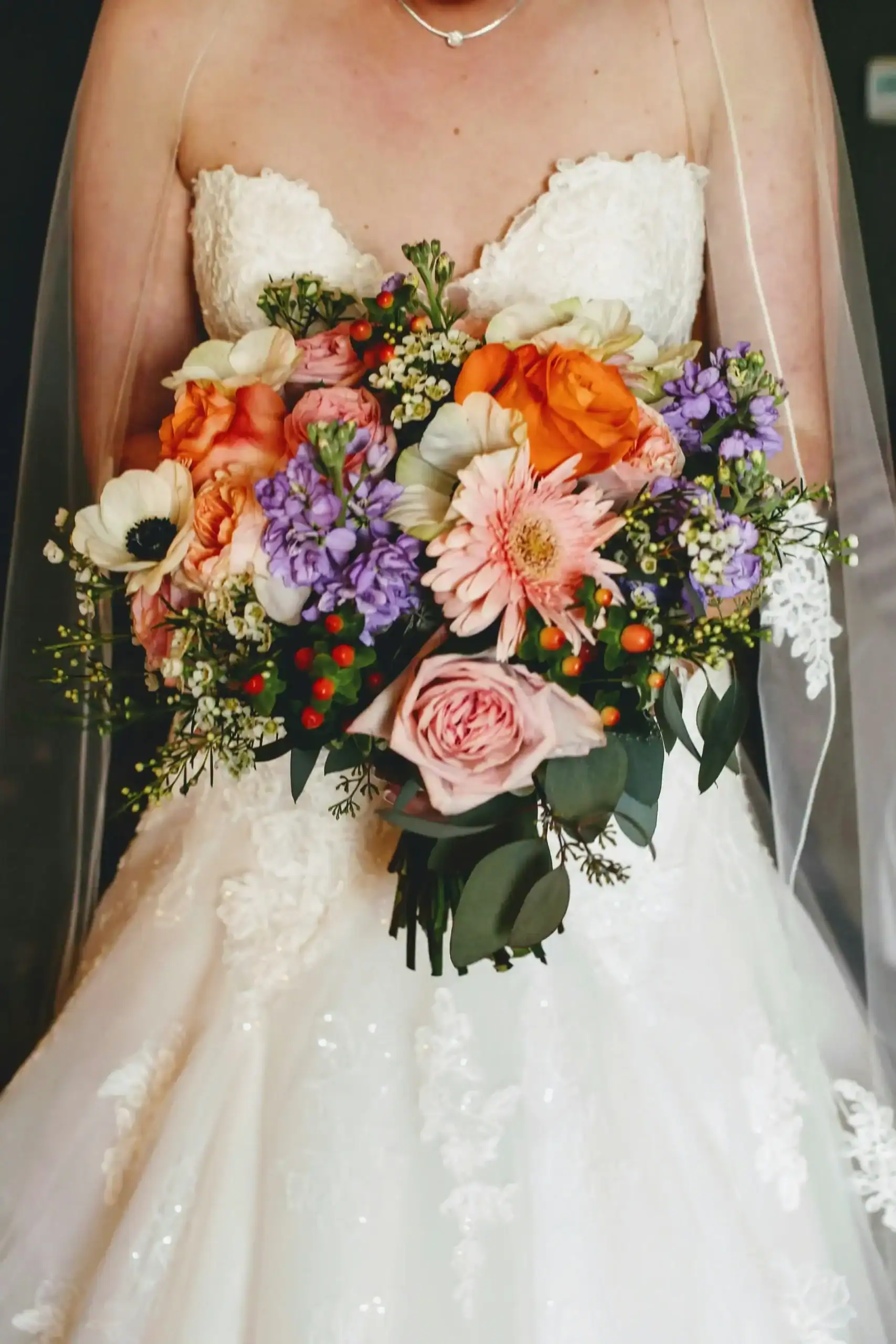 Bright floral wedding bouquet with roses, daisies, and greenery.