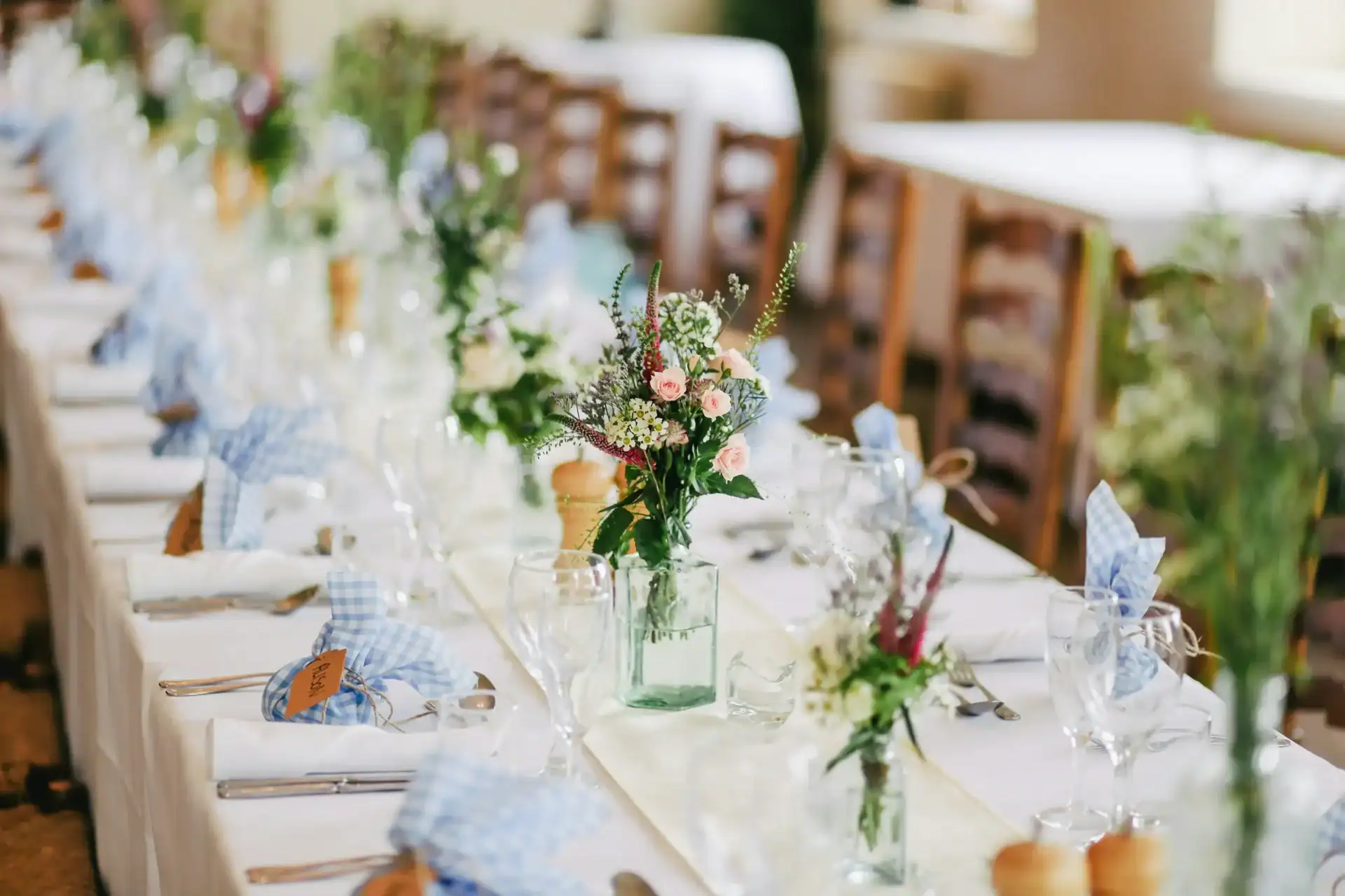 Beautiful floral centrepiece with pink roses and greenery on a wedding reception table.